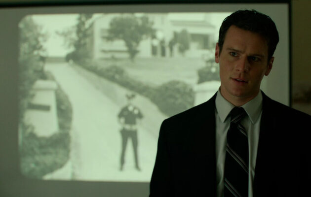 Man in a suit presenting an investigation on a projector.