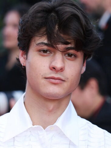 Close-up portrait of a young man with dark wavy hair.