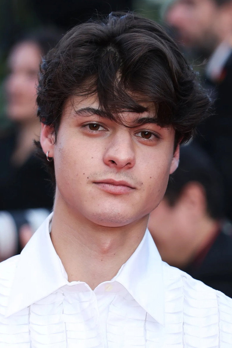 Close-up portrait of a young man with dark wavy hair.