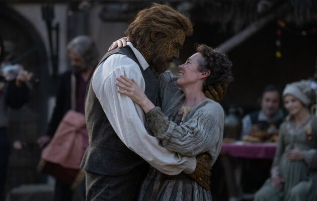 A woman and a man with textured skin embrace warmly.